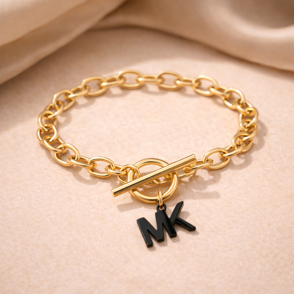 Gold chain bracelet with MK charm on a beige fabric background